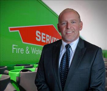 Man in suit with SERVPRO picture in the background