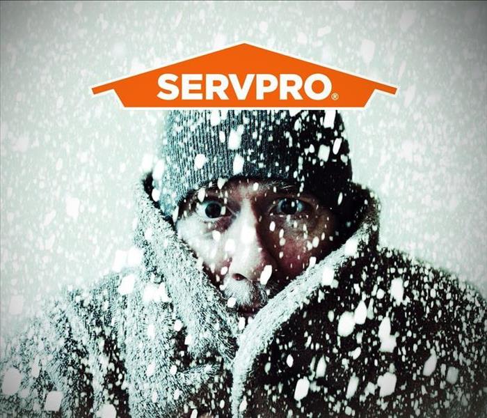 A man bundled up during a heavy snowfall along with the SERVPRO logo